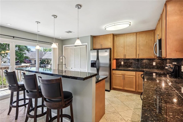 kitchen with a center island with sink, backsplash, pendant lighting, and a wealth of natural light