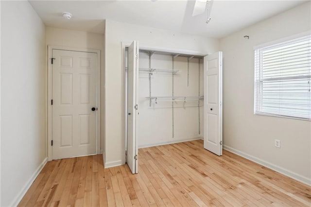 unfurnished bedroom with light hardwood / wood-style flooring, ceiling fan, and a closet