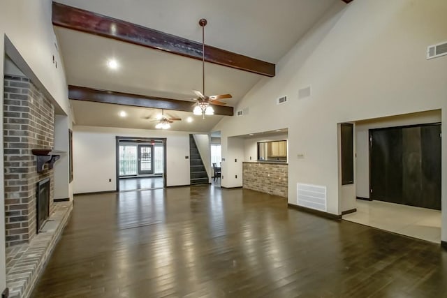 unfurnished living room featuring a fireplace, beamed ceiling, hardwood / wood-style flooring, and ceiling fan