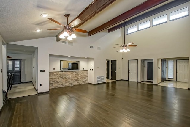 unfurnished living room featuring hardwood / wood-style flooring, beamed ceiling, ceiling fan, a textured ceiling, and high vaulted ceiling