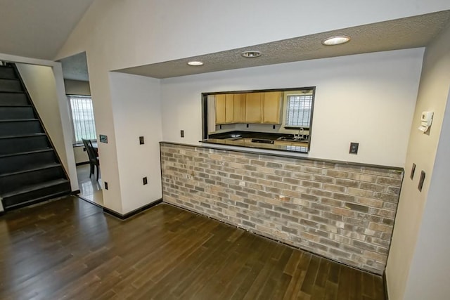 bar featuring dark wood-type flooring, light brown cabinetry, plenty of natural light, and a textured ceiling