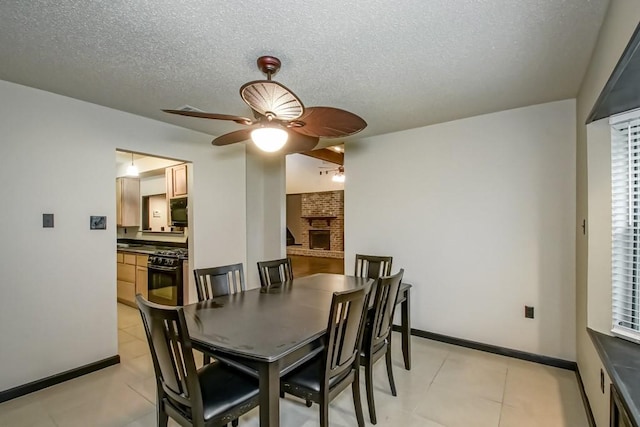 dining space with a brick fireplace, ceiling fan, and a textured ceiling