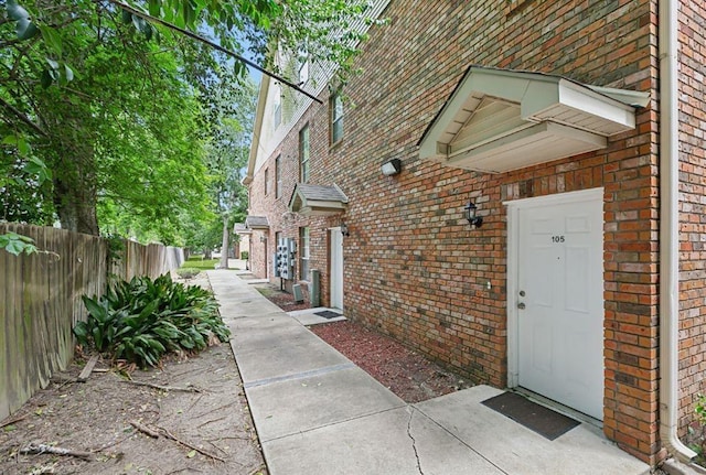 view of side of property featuring fence and brick siding