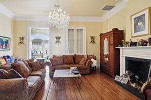 living room with hardwood / wood-style flooring, crown molding, and a notable chandelier