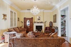 living room featuring hardwood / wood-style floors, ornamental molding, and a chandelier