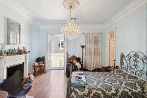 bedroom with wood-type flooring, a chandelier, and ornamental molding