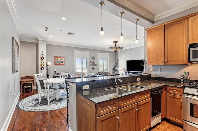 kitchen with hanging light fixtures, light hardwood / wood-style flooring, stove, dark stone counters, and sink