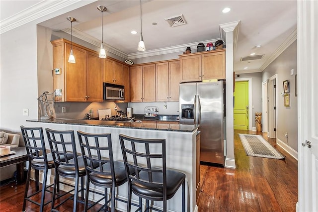 kitchen with decorative light fixtures, dark hardwood / wood-style flooring, appliances with stainless steel finishes, and kitchen peninsula