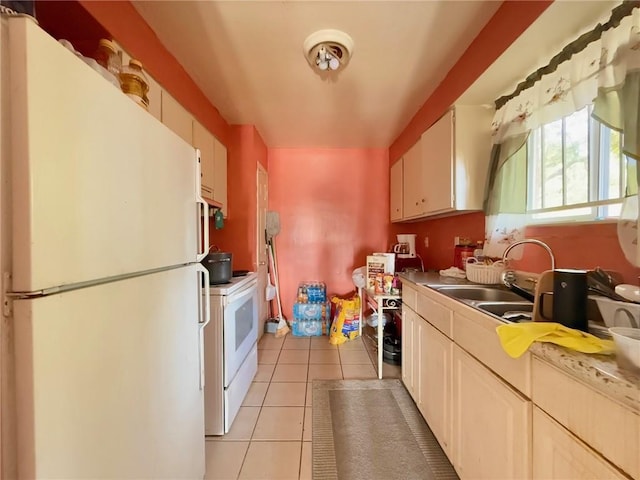 kitchen featuring sink, white appliances, white cabinetry, and light tile patterned flooring