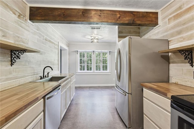 kitchen featuring appliances with stainless steel finishes, wooden counters, sink, and crown molding