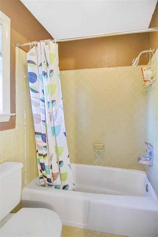 bathroom featuring tile floors, shower / bathtub combination with curtain, and toilet