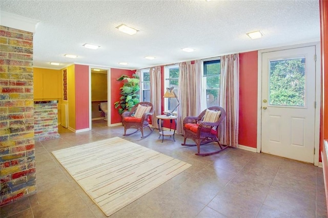 living area with a textured ceiling, brick wall, and tile flooring