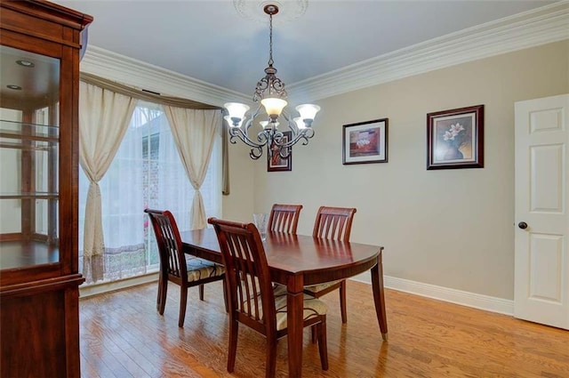 dining space featuring crown molding, an inviting chandelier, and light hardwood / wood-style flooring