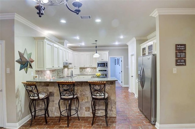 kitchen with crown molding, hanging light fixtures, backsplash, stainless steel appliances, and kitchen peninsula