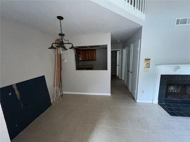 unfurnished living room with a notable chandelier, a tile fireplace, and light tile floors