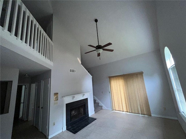 unfurnished living room featuring high vaulted ceiling, tile flooring, ceiling fan, and a fireplace