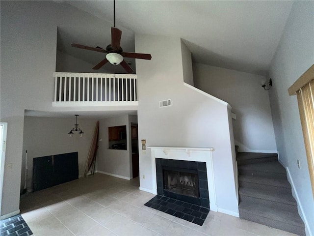 unfurnished living room with a tiled fireplace, ceiling fan, high vaulted ceiling, and light tile floors