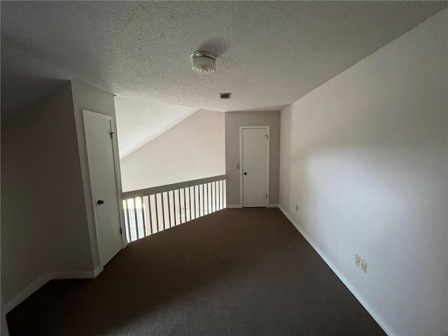 interior space featuring a textured ceiling, carpet floors, and vaulted ceiling