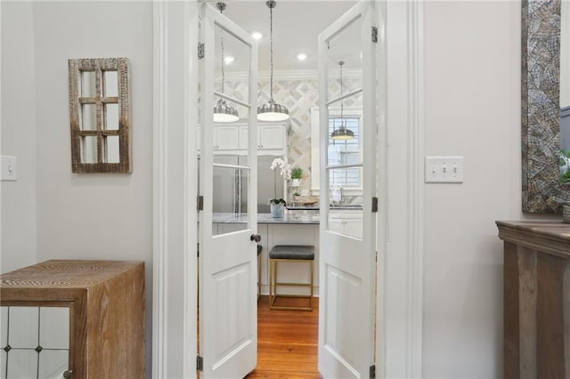 hallway with light hardwood / wood-style floors and crown molding