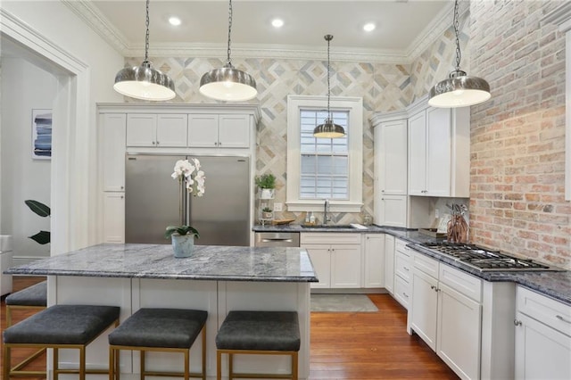 kitchen featuring hardwood / wood-style flooring, appliances with stainless steel finishes, hanging light fixtures, and a center island