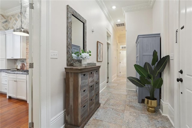 hall featuring light tile floors and ornamental molding