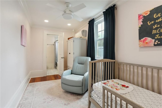 bedroom with ornamental molding, wood-type flooring, a nursery area, and ceiling fan