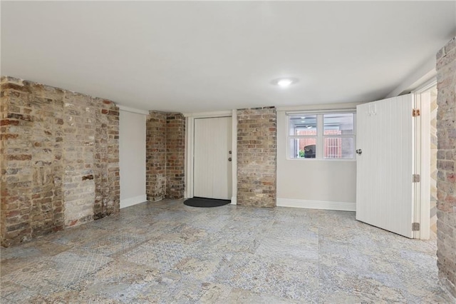 spare room featuring brick wall and tile floors