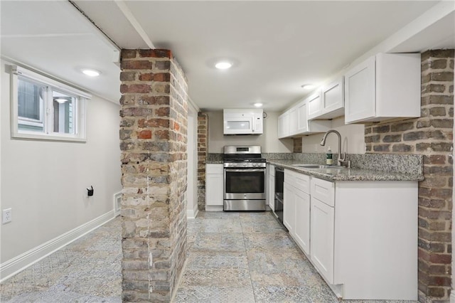 kitchen with stainless steel stove, white cabinetry, sink, and light tile flooring