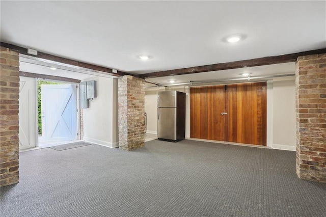 basement featuring stainless steel refrigerator, a barn door, brick wall, and dark carpet