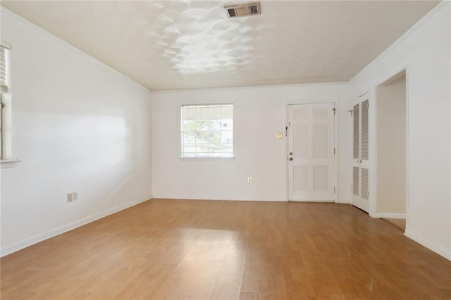 spare room featuring wood-type flooring and crown molding