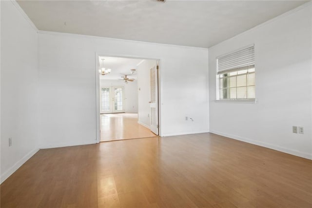 empty room featuring hardwood / wood-style floors, ornamental molding, and ceiling fan with notable chandelier