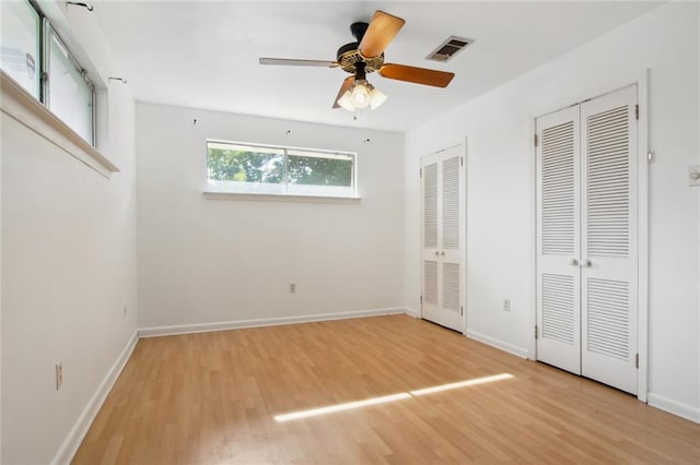 unfurnished bedroom featuring multiple closets, light hardwood / wood-style flooring, and ceiling fan