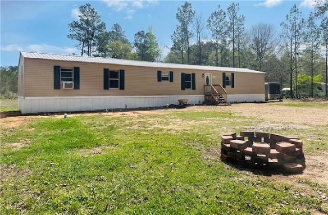 back of property featuring a fire pit and a yard