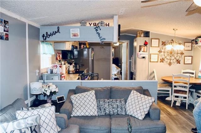 living room featuring a textured ceiling, ceiling fan with notable chandelier, wood finished floors, and lofted ceiling