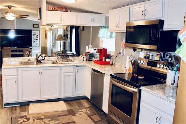 kitchen featuring ceiling fan, white cabinetry, dark hardwood / wood-style flooring, lofted ceiling, and stainless steel appliances