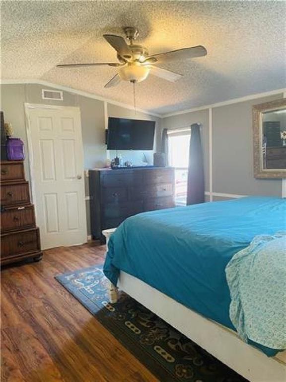 bedroom with hardwood / wood-style floors, ceiling fan, ornamental molding, and a textured ceiling