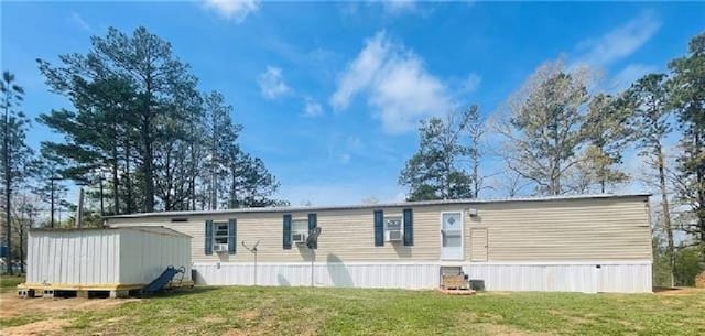 rear view of property featuring a storage unit, a lawn, and an outdoor structure