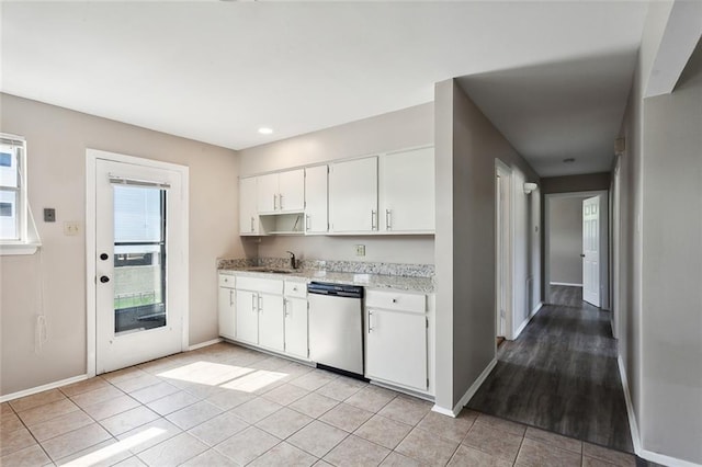 kitchen featuring white cabinets, sink, light tile floors, and stainless steel dishwasher