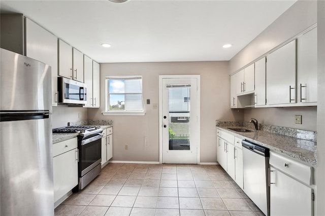 kitchen featuring light stone counters, white cabinetry, stainless steel appliances, and light tile floors