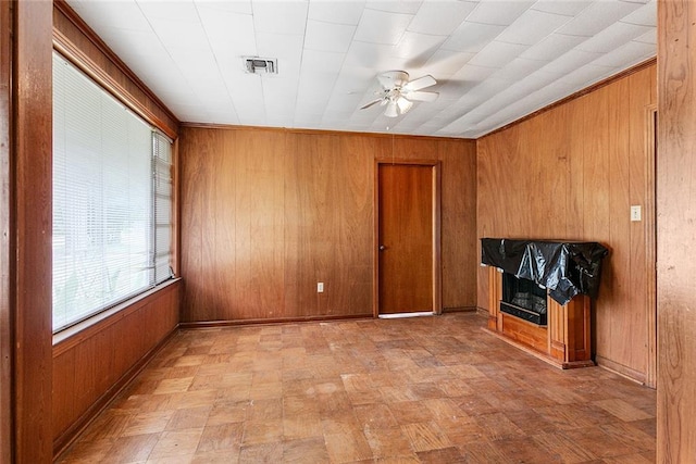 unfurnished living room featuring a fireplace, wood walls, and ceiling fan