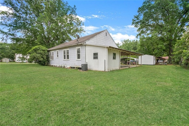 back of house with central air condition unit, a lawn, and a storage unit