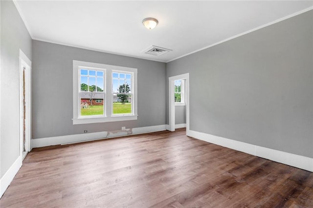 empty room featuring plenty of natural light, hardwood / wood-style floors, and crown molding