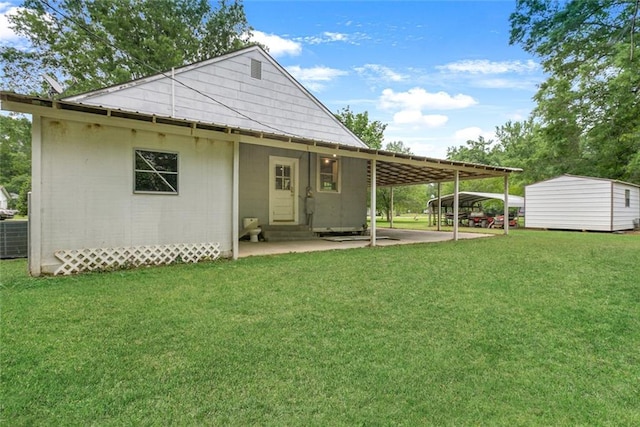 back of house with a yard, a carport, and a storage unit