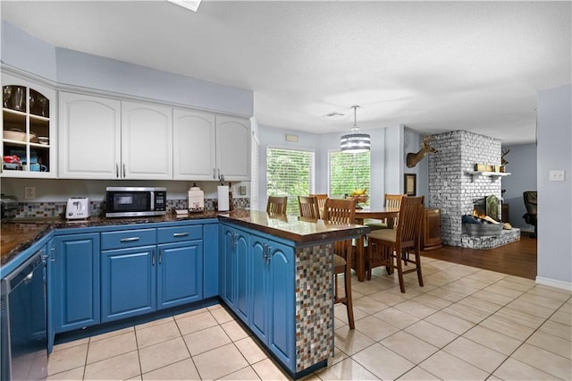 kitchen featuring blue cabinets, hanging light fixtures, light tile patterned floors, dishwashing machine, and white cabinets