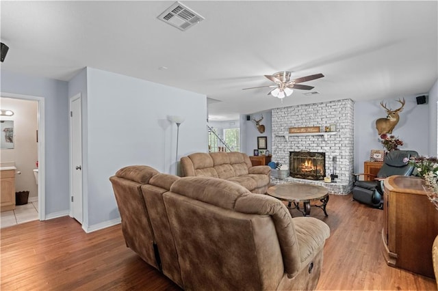 living room featuring ceiling fan, a fireplace, and light hardwood / wood-style flooring