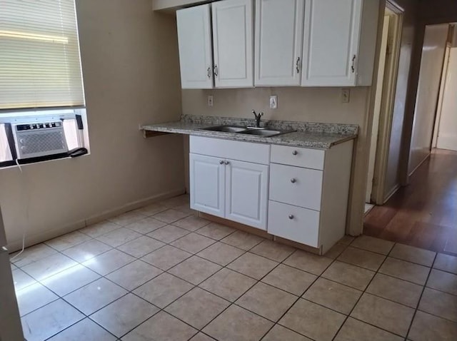 kitchen featuring sink, white cabinets, light tile floors, and light stone counters