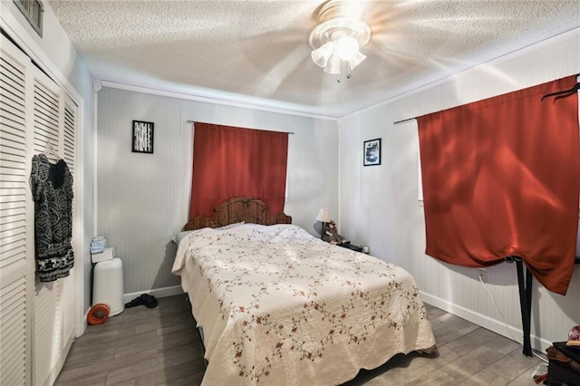 bedroom featuring a textured ceiling, ceiling fan, crown molding, dark wood-type flooring, and a closet