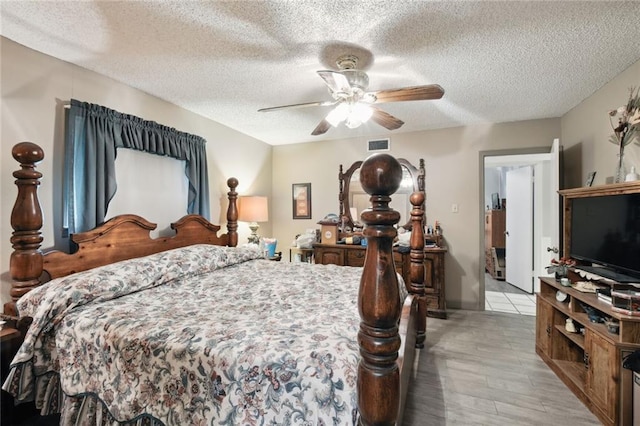 bedroom with light wood-type flooring, a textured ceiling, and ceiling fan