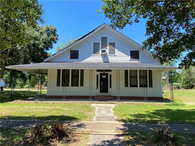 country-style home featuring covered porch and a front lawn