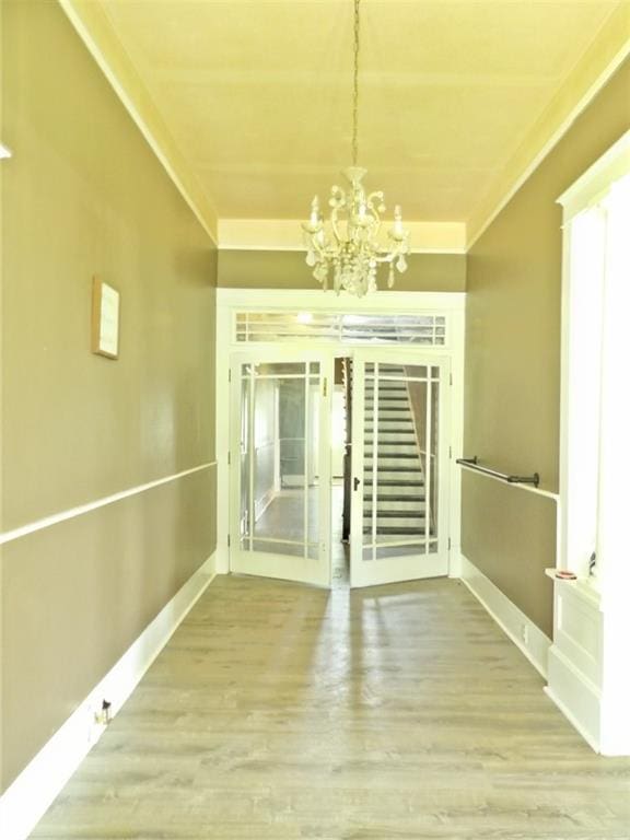 interior space with a notable chandelier, hardwood / wood-style flooring, and crown molding